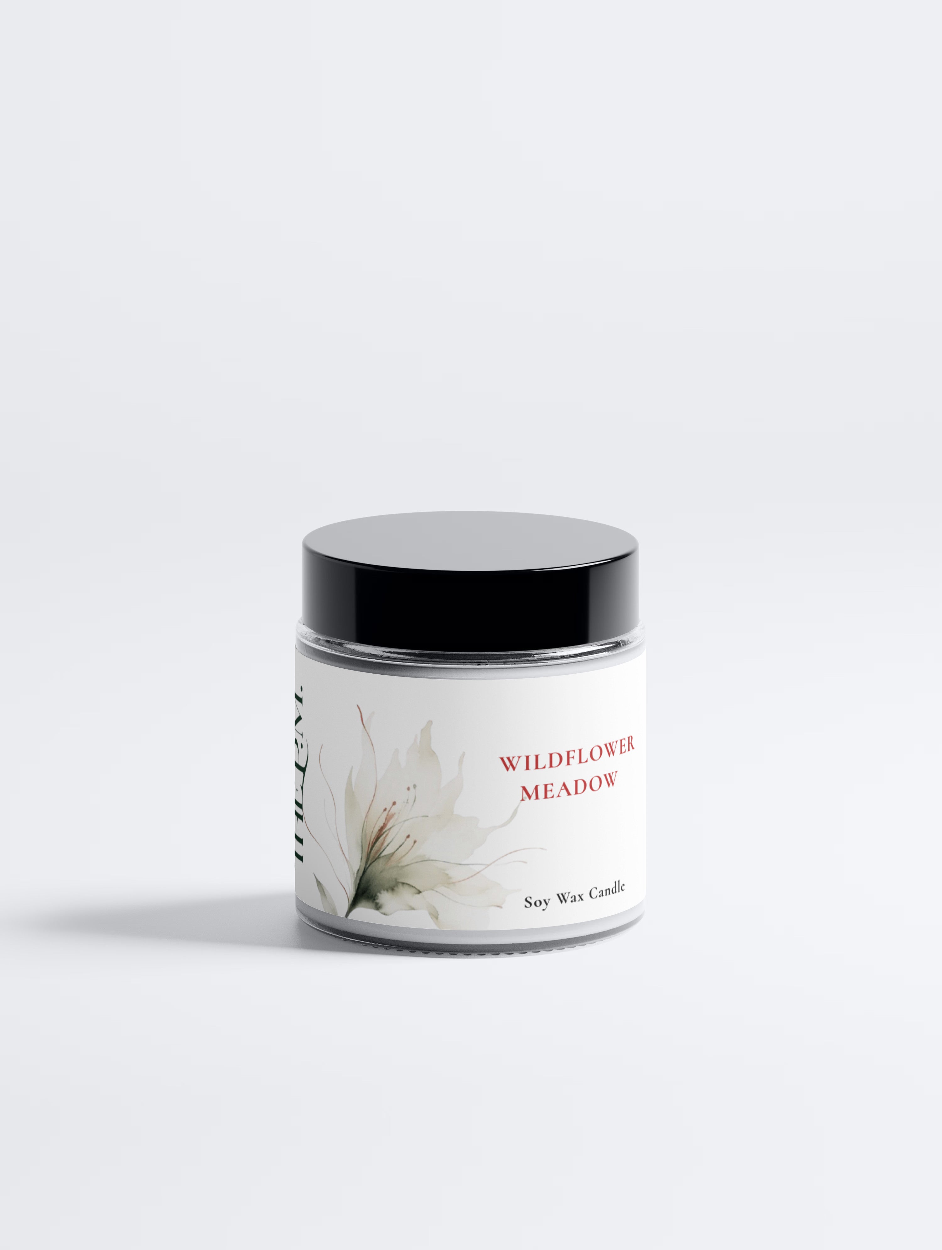 A soy wax candle in a clear glass jar with a black lid and a white label featuring a watercolor wildflower and the text 'WILDFLOWER MEADOW' and 'Soy Wax Candle'.