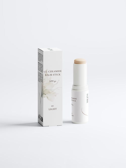 A white cosmetic stick and its matching white box with black text, photographed on a clean light gray studio background. The product appears to be a ceramide balm stick with SPF 30.